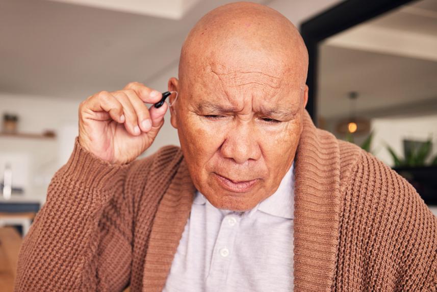 A man putting a hearing aid in his ear