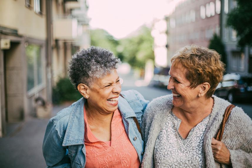 Two women laughing together, walking outside