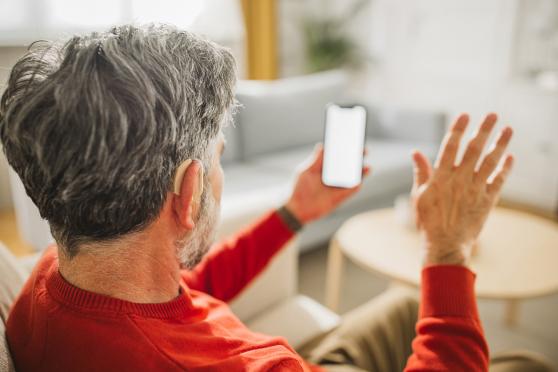 Man with a hearing aid looking at a phone