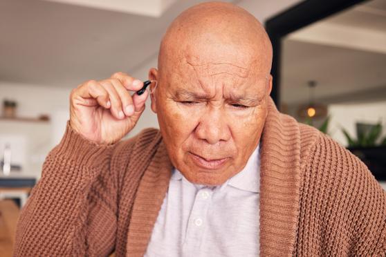 A man putting a hearing aid in his ear