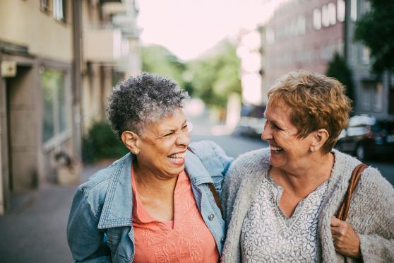 Two women laughing together, walking outside